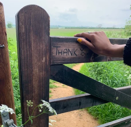 Hand on a gate with the words 'Thank You' etched in